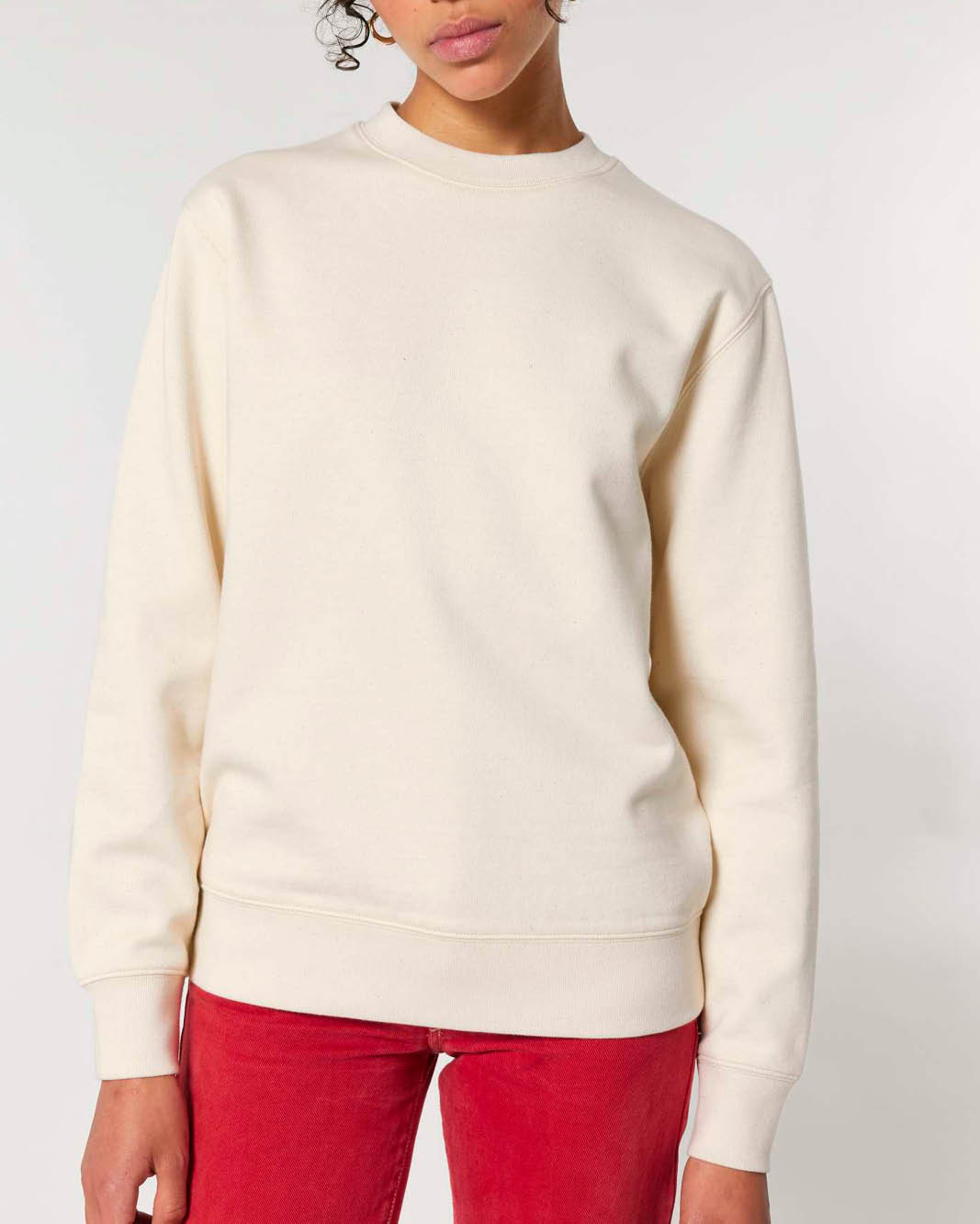 A person wearing a natural oversized crewneck sweatshirt with cuffed sleeves, waistband and neckline.