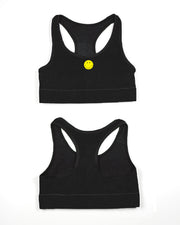 A black racerback sports bra displaying the front with a small yellow smiley face button at the center.