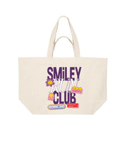 A natural oversized canvas tote bag with a colorful graphic print that reads 'SMILEY RUN CLUB' in purple and white, decorated with cartoon smiley faces and small colorful icons.