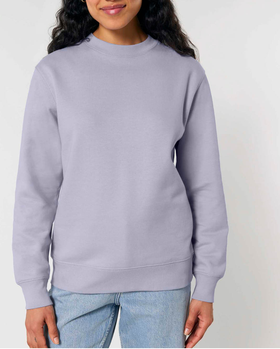 A woman wearing a light lavender gender-neutral crewneck sweatshirt. With ribbed waist-band, neckline and wrist cuffs.